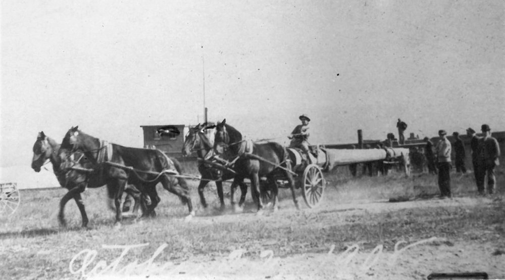 An archival photo, dated October 11, 1908, showing the first wooden flagpole being brought into Marlboro by a horse-drawn wagon.